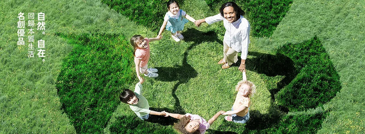 Kinder und eine Erwachsene bilden Hand in Hand einen Kreis auf einer Wiese in Form des Recycling-Symbols